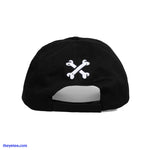 On the back of the black hat above the black size strap are two white embroidered bones crossed together to form an X shape. - Cursed With Glowing Bones Hat