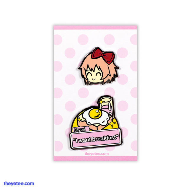 Set includes a cheery Sayori wearing a red hair bow. Second pin is an egg on toast with the caption," I want breakfast!" - Sayori Pin Set