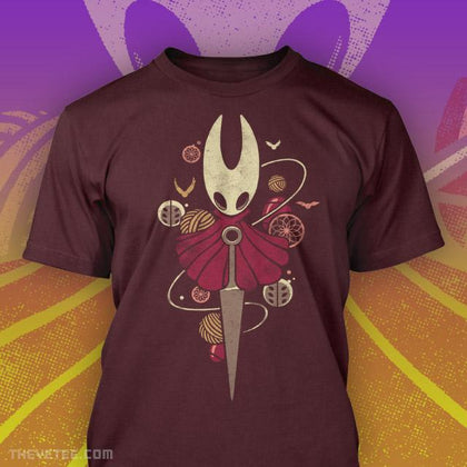 Red tee shirt, the Hornet is centered with a Sharpened Nail. Around them are balls of thread. 