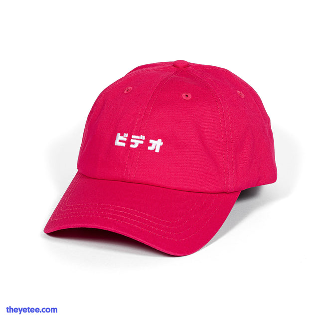 A dad hat style cap in the color magenta with matching fastener on the back. Embroidered in white is the kanji for "video". - Bideo Cap (Magenta)