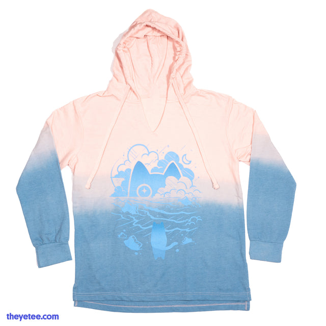 Garment is a pink to blue ombre longsleeve with hood. Design is Amaro on a beach while a cat peer's from behind the clouds. - Eva Amaro