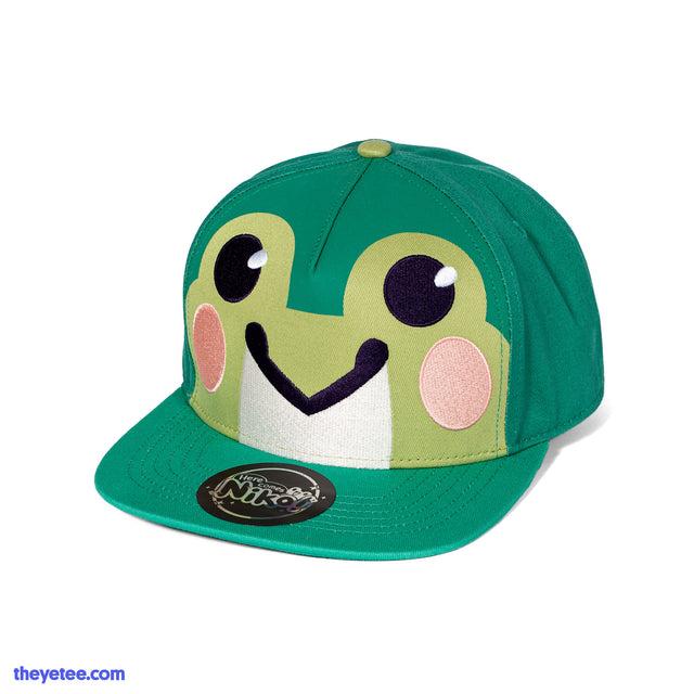 Green hat with cute frog face front of the cap in lighter yellow-green. Frog has pink blush marks. Hat bill has round sticker - Niko Frog Hat