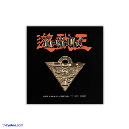 Hard enamel pin of Yugi's gold Millenium Puzzle piece, an upside down triangle with an eye on the front and half ring on top