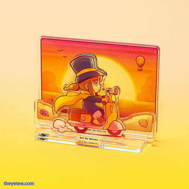 Acrylic stand of Hat Kid riding a yellow scooter along a sandy beach at sunset with hot air balloon and seagulls in the sky. - Sunset