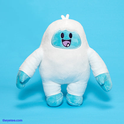 A white Yetee with light blue feet and hands. Smiling adorably with two tufts of hair on top of its head. 